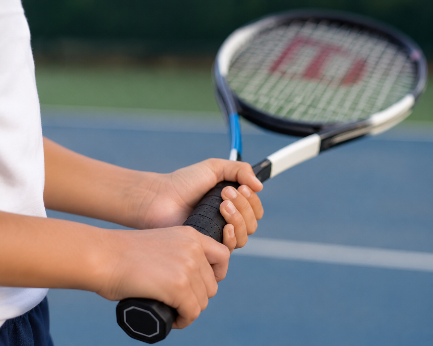 Beginner tennis player holding a racquet handle on court.