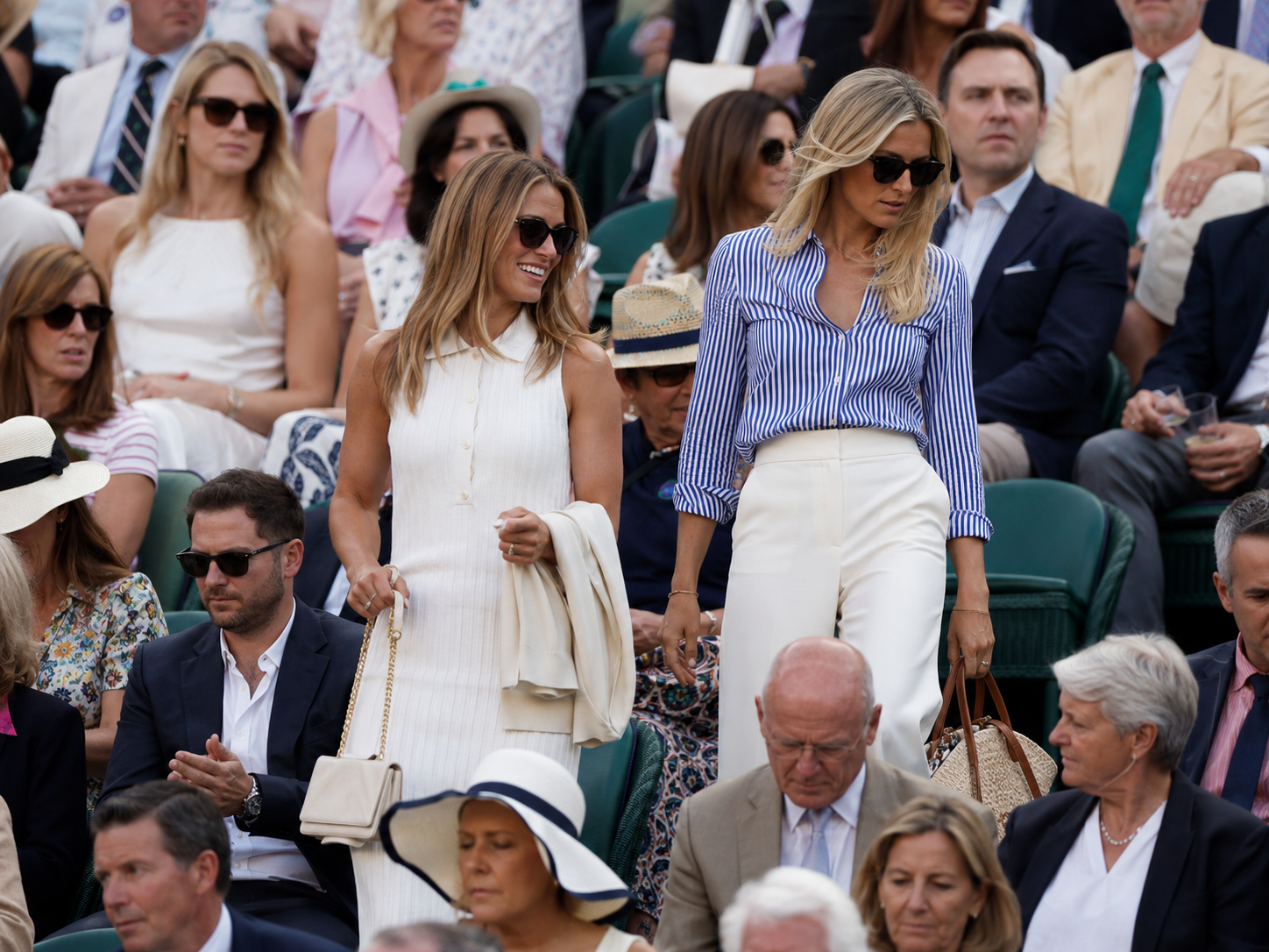 Stylish Wimbledon spectators in summer outfits watching tennis from the stands.